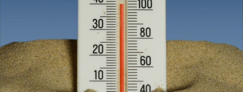 A thermometer in the sand with a blue sky in the background